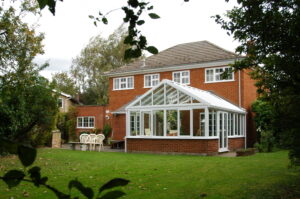 Alt text: A modern lean-to conservatory with large glass panels and a garden view