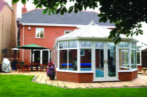 Interior view of a P-shaped conservatory set up as a dining area with garden views.